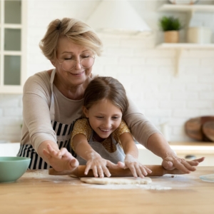 Nonna e nipote che stendono la pasta con complicità e giocosità