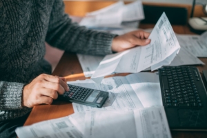 Persona che esamona documenti economici e fa conteggi con una calcolatrice.